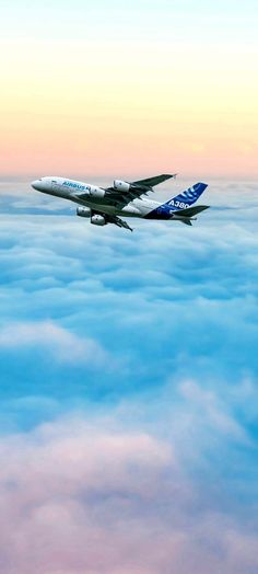 an airplane flying above the clouds at sunset