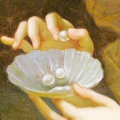 a close up of a person holding a shell with pearls in its palm and two hands