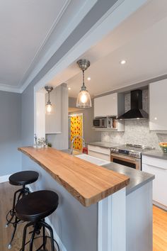 a kitchen with an island and two stools in front of the counter top that is made out of wood