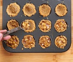 a person scooping some food out of a muffin tin