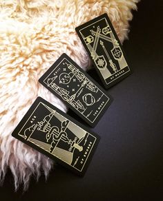 three black and gold playing cards laying on a white fur covered floor next to each other