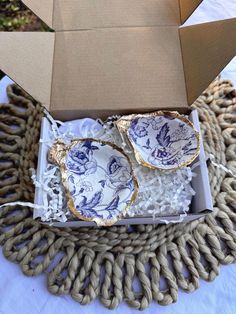 an open box with two plates in it sitting on top of a woven table cloth