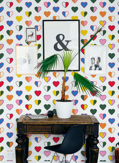 a desk with a potted plant on it in front of a colorful wallpaper