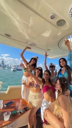 a group of people on a boat posing for the camera with their arms in the air