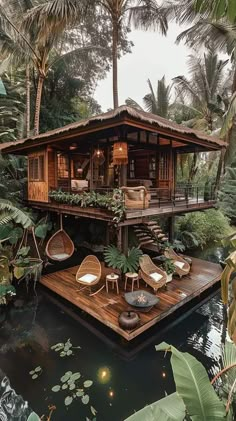 a wooden house sitting on top of a river surrounded by trees and greenery in the jungle