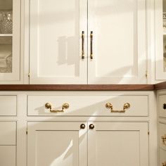 a kitchen with white cabinets and gold handles on the doors, drawers and cupboards