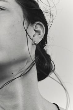 black and white photograph of a woman with ear piercings on her ears, looking to the side