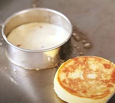 a pancake sitting on top of a table next to a metal container filled with liquid