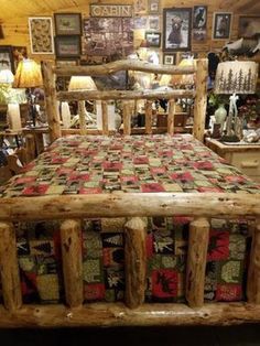 a log bed frame with quilted bedspread in a room full of pictures