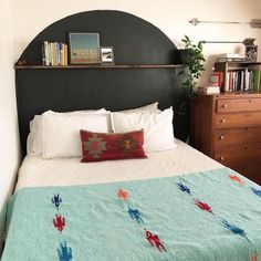 a bedroom with a bed, dresser and bookshelf on the wall above it