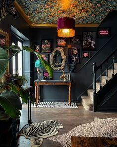 a living room filled with lots of furniture next to a stair case covered in pictures