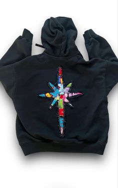 a black hoodie with a colorful cross on the front and back, all over it