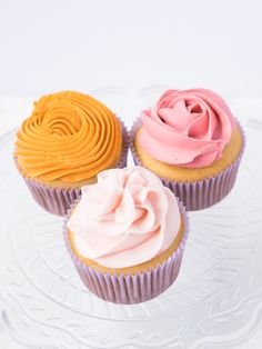 three cupcakes on a glass plate with frosting in the middle and swirl designs