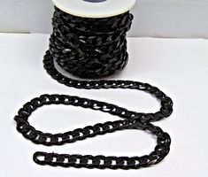 a spool of black chain next to a spool of thread