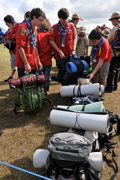 several people in red shirts and backpacks looking at items on the ground