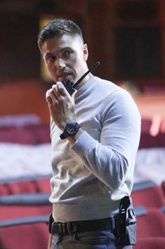 a man holding something in his hand while standing next to a red velvet auditorium seat