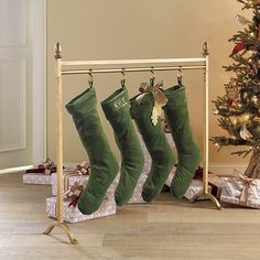 three christmas stockings hanging from a rack next to a christmas tree