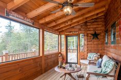 the inside of a cabin with wooden walls and flooring, ceiling fan and windows