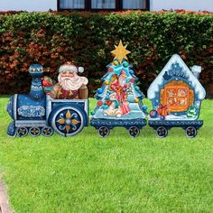 an outdoor christmas scene with santa and his train in the grass next to a hedge