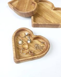 two wooden heart shaped trays with rings on them