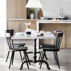 a kitchen table with four chairs and a white counter top in front of an oven