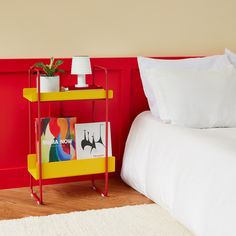 a yellow shelf next to a white bed