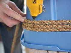 a person using a drill to attach rope on a blue container with a yellow screwdriver