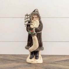 a statue of santa claus holding a christmas stocking on top of a wooden table