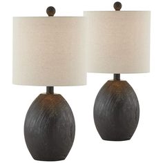 two black ceramic lamps with white shades on each lamp and one light brown shade on the other