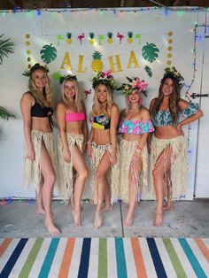 four beautiful women in bikinis standing next to each other with hula skirts on