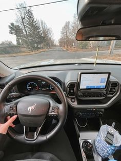 a person driving a car on the road with their hands on the steering wheel and dashboard