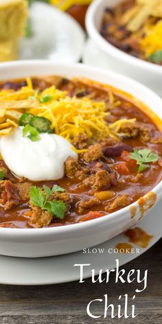 a bowl of turkey chili with sour cream and tortilla chips on the side