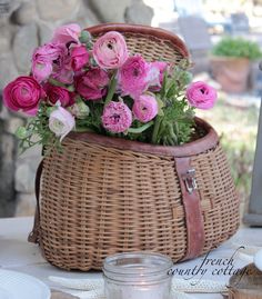 a wicker basket filled with pink flowers on top of a table