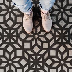 a person standing in front of a black and white floor with geometric design on it