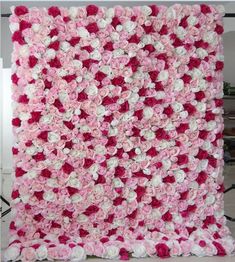 pink and white crocheted blanket with roses on the bottom, in front of a wall