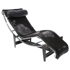 a black leather chaise lounge chair with metal frame and footrests on an isolated white background