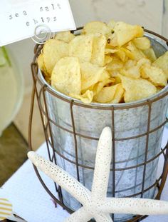 a metal bucket filled with chips next to a starfish on top of a table