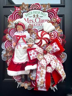 a christmas wreath with candy canes and santa claus's outfit on it, sitting in front of a door