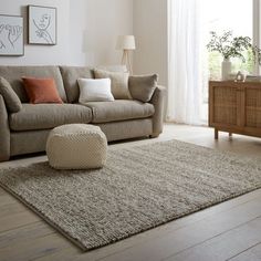 a living room scene with focus on the couch and rug, which has been placed in front of a window