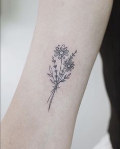 a small flower tattoo on the left side of the arm is shown in black ink