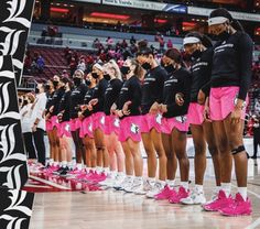 the women's basketball team is lined up in pink shorts and black shirts with matching shoes