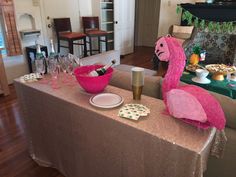 a pink flamingo sitting on top of a table next to plates and cups filled with food