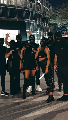 a group of people standing around each other wearing black masks and holding knives in their hands