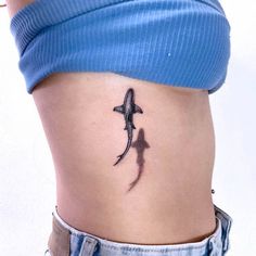 a woman's stomach with a small tattoo of a shark on the side of her belly