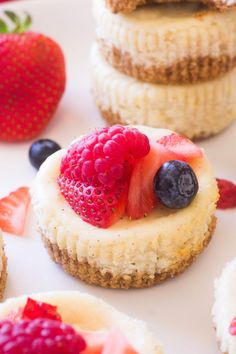 small desserts are arranged on a plate with berries and cream cheesecake toppings