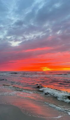 the sun is setting over the ocean with waves coming in to shore and pink clouds