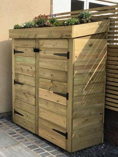 a wooden storage shed with plants growing on top