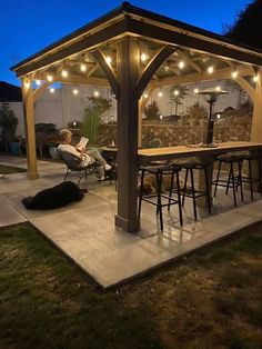 a dog laying on the ground in front of a covered patio area with lights strung around it