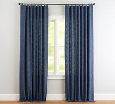 a blue curtain hanging in front of a window with white walls and wooden flooring