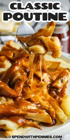 a plate with french fries covered in gravy and being held by a fork